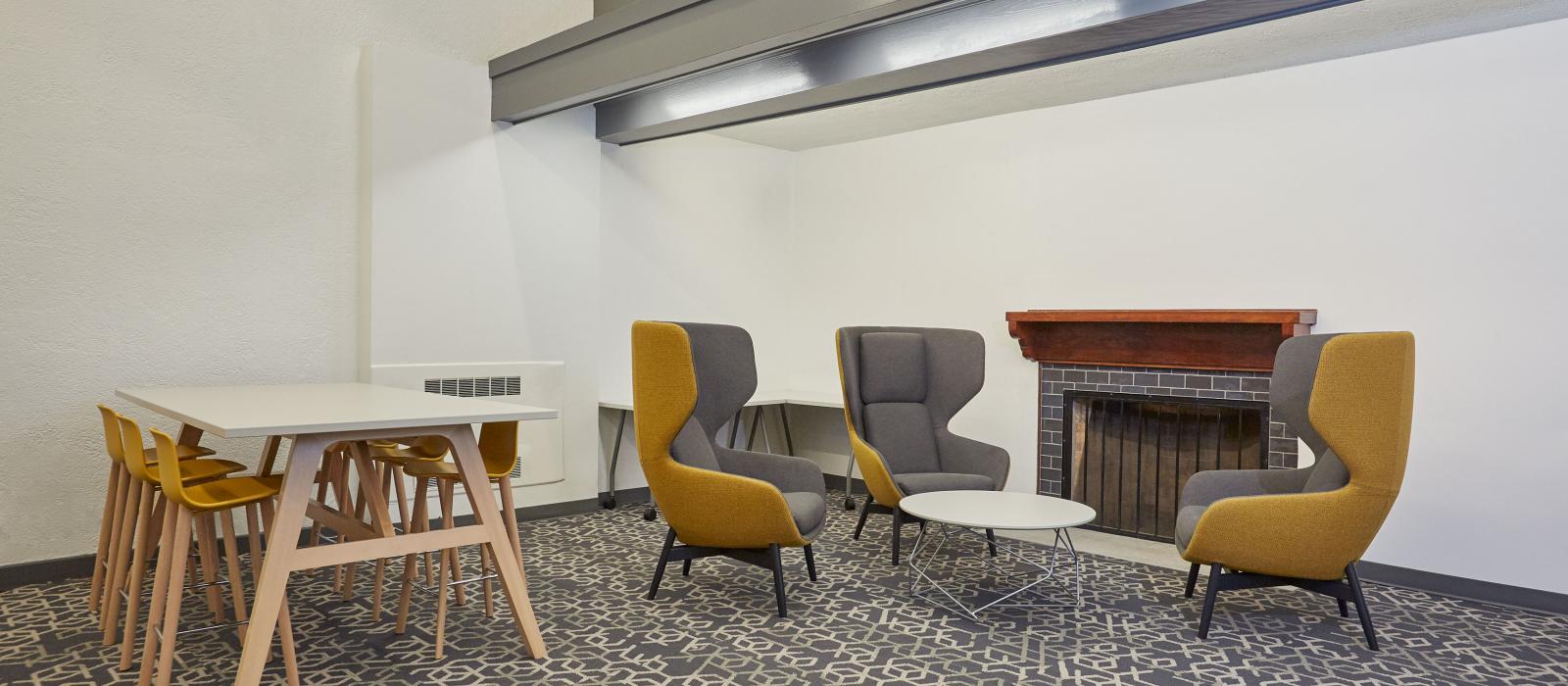 Lounge area with chairs around a fireplace and a tall table with barstools.