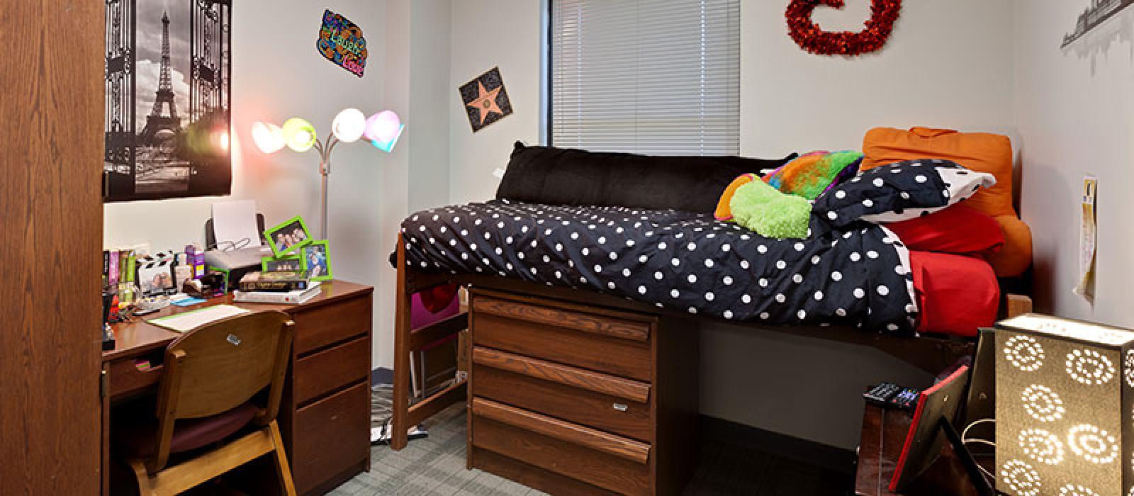 Bedroom with a desk, a raised bunk bed with a drawer underneath it.