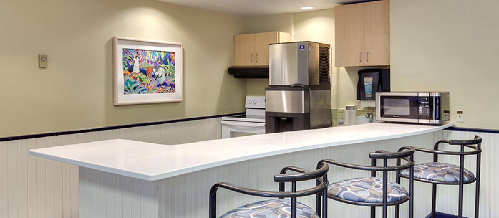 Kitchen. Bar counter, three bar stools, typical kitchen appliances.