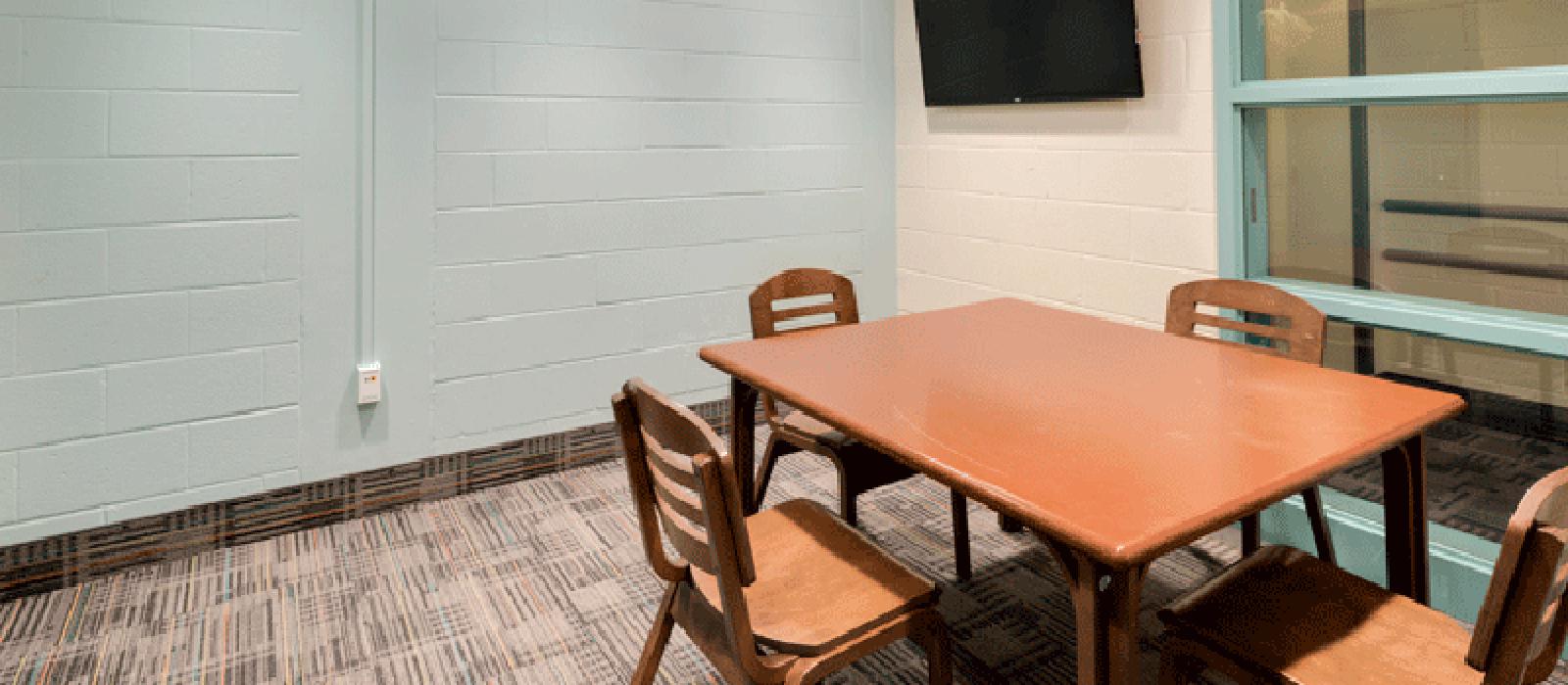 Study room with table and chairs, and a TV monitor on the wall.