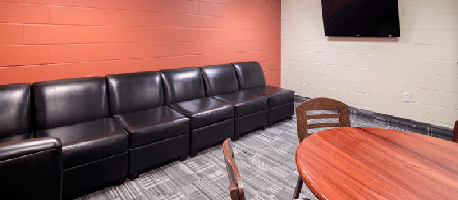 Study room with a sofa, a table and chairs, and a TV monitor on the wall.