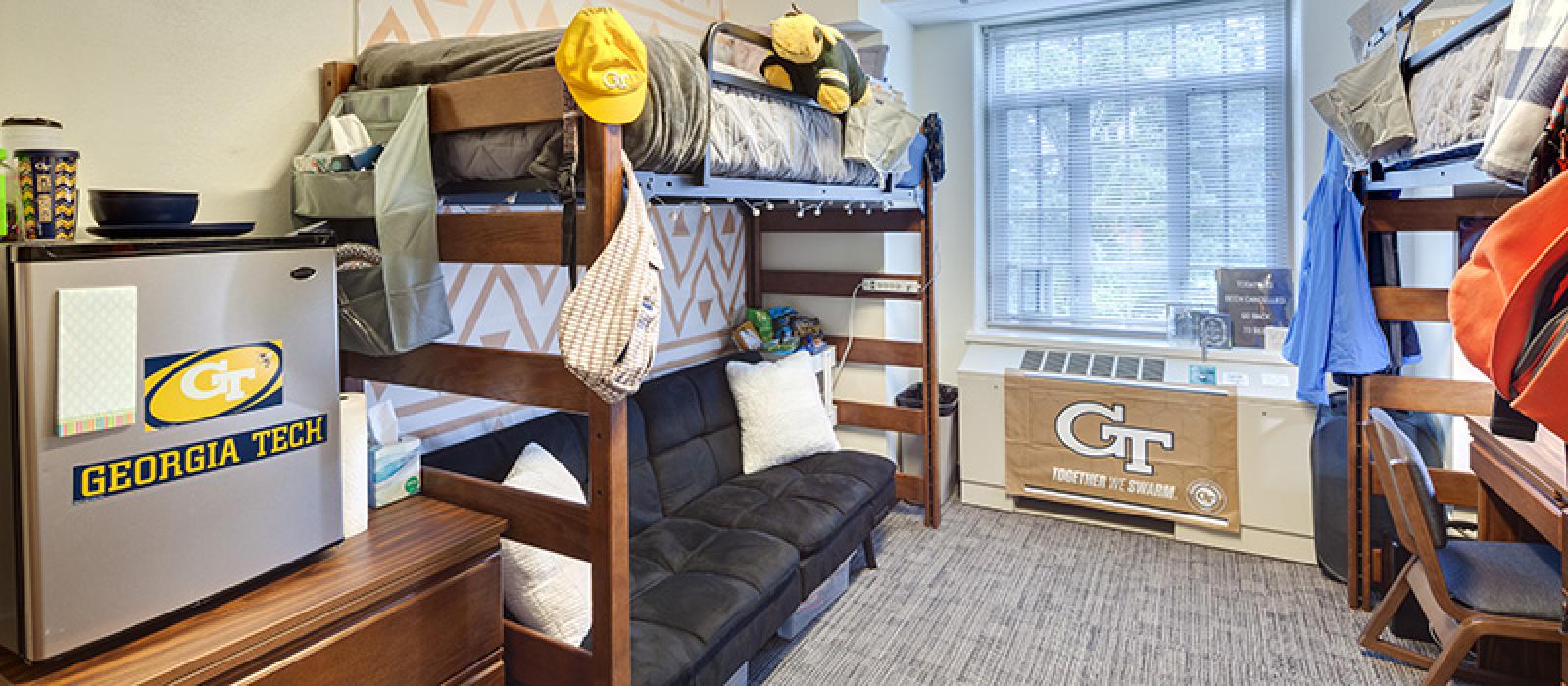 Bedroom with bunk beds. One with a sofa underneath, another one with a desk.