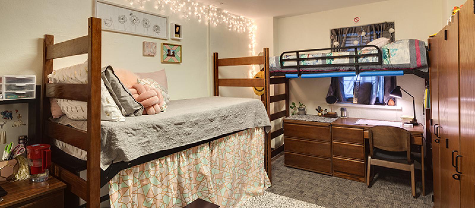 Bedroom. One bunk bed with a desk underneath another one risen enough to use as storage space.