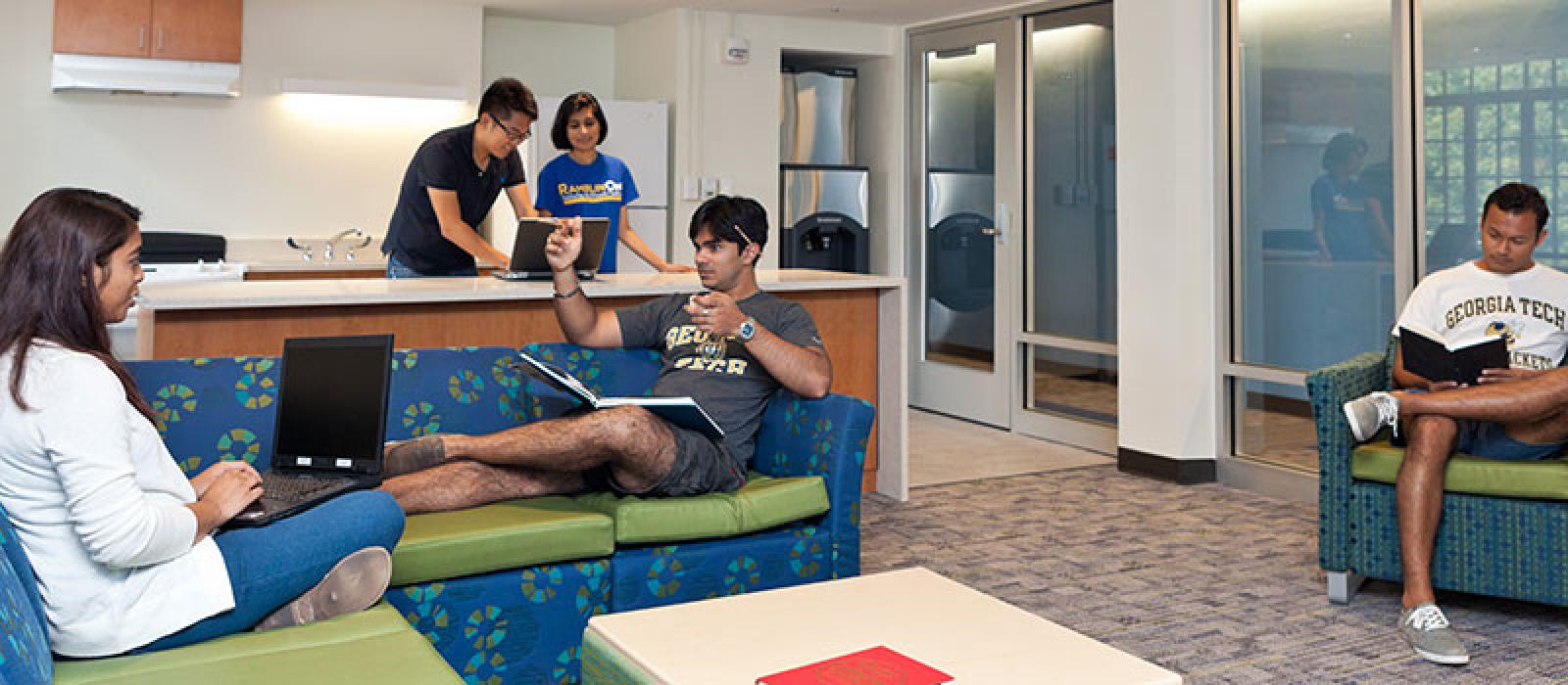 Students in the lounge area. There are sectional sofas and a full kitchen.