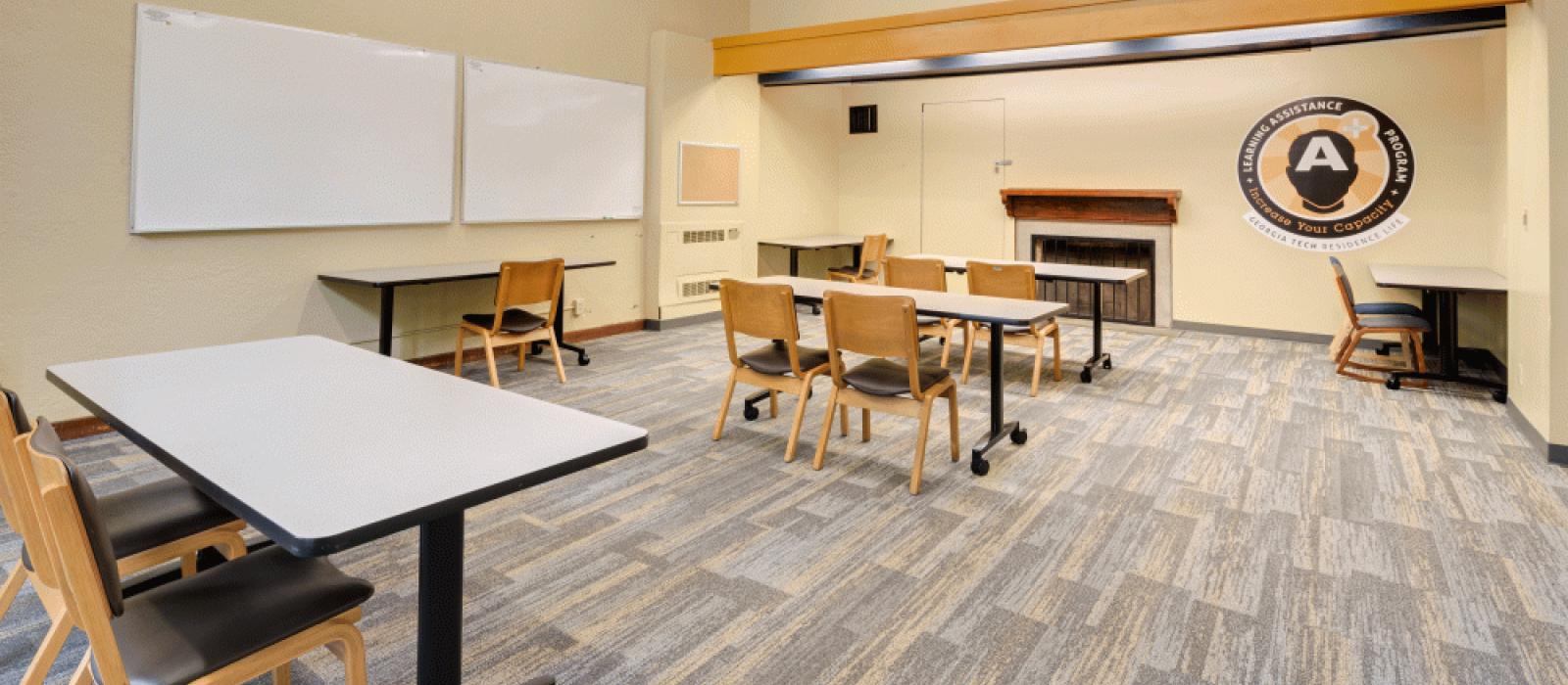 Learning center with long tables and chairs and white boards on the wall.