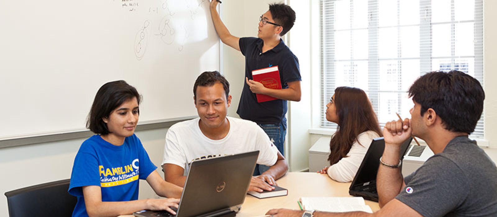 Students looking at a computer and a white board.