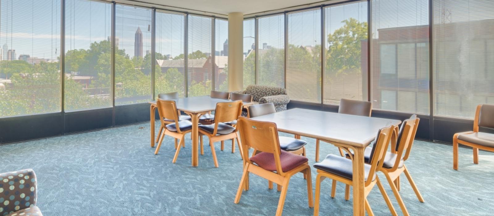 Lounge with a love seat, table and chairs, and walls made up glass pane windows.