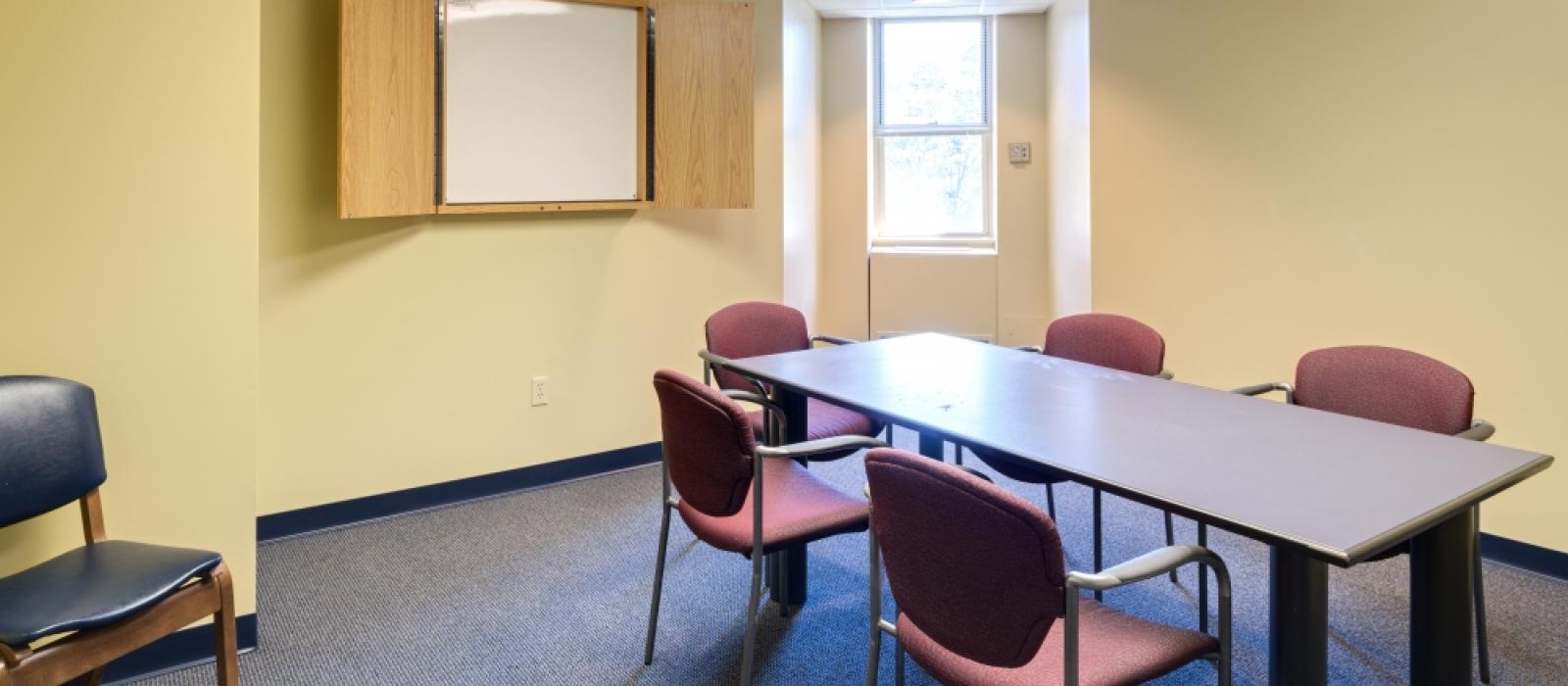 Study room with a table and chairs, and a white board.